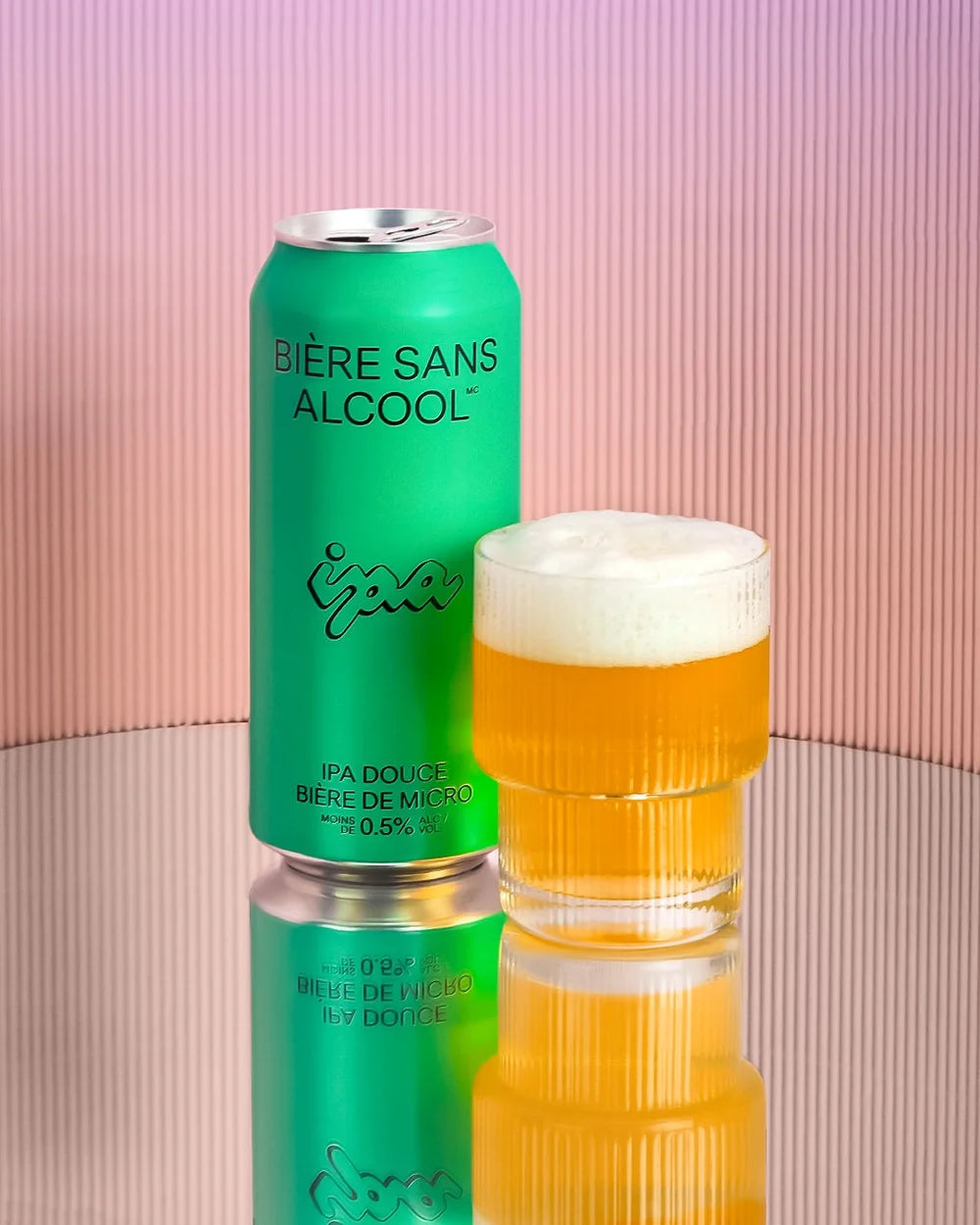 Green can of 'Bére Sans Alcool' with a glass of beer on a reflective surface.