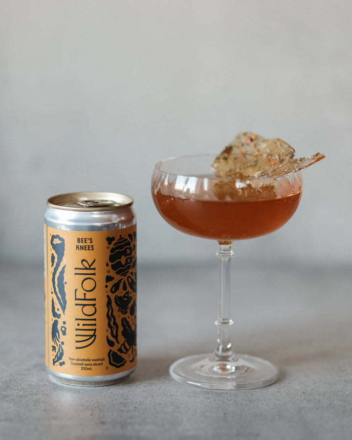 Cocktail in a glass with a can of Wild Folk on a gray background