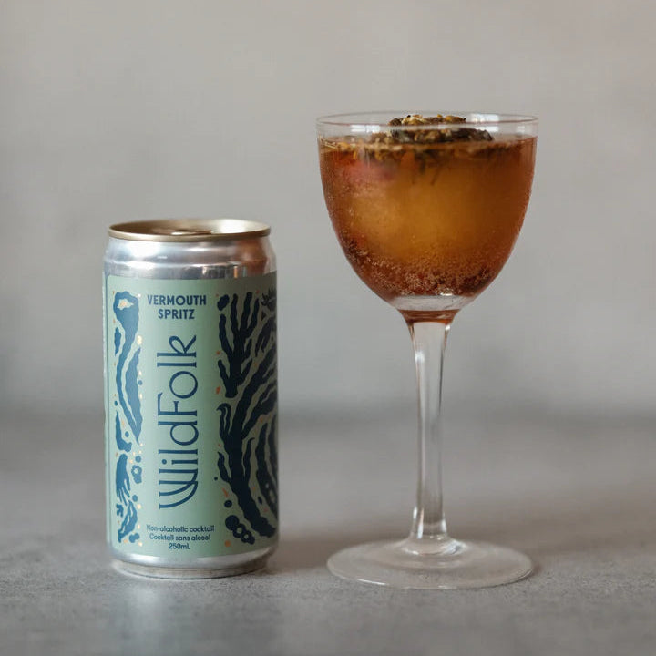 Cocktail in a glass with a can labeled 'Wildfolk' on a neutral background